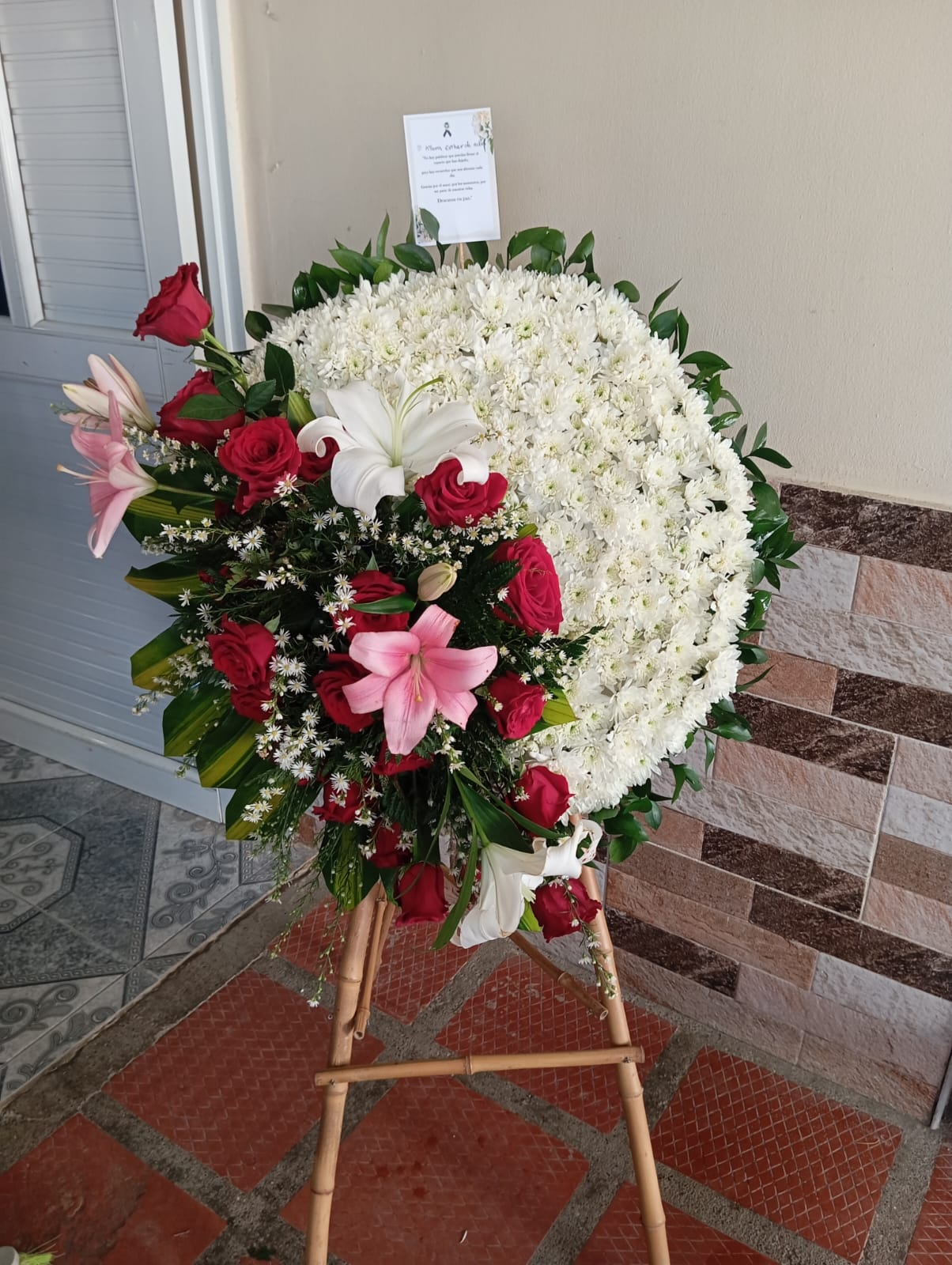 Corona fúnebre blanca con rosas rojas y lirios