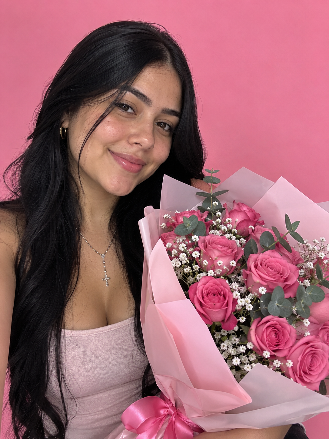 Clienta sonriendo con un ramo de rosas rosadas recién entregado